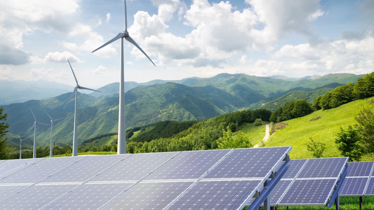 Solar panels and wind turbines in green hills